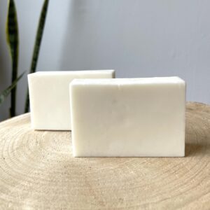 Two white bars of soap on wood.