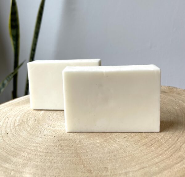 Two white bars of soap on wood.