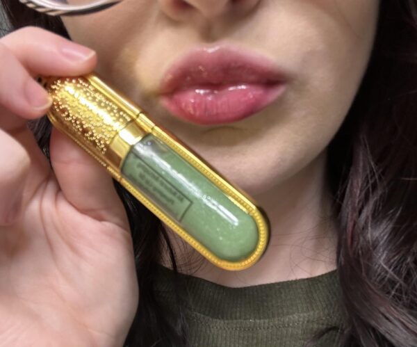 Person holding green lip gloss tube.