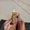 Golden shimmer body oil bottle in hand.