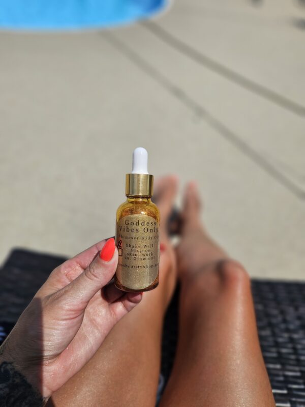 Golden shimmer body oil bottle in hand.