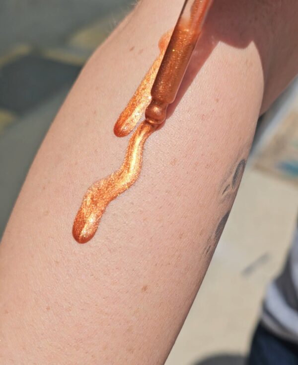 Shimmery gold liquid being applied to skin.