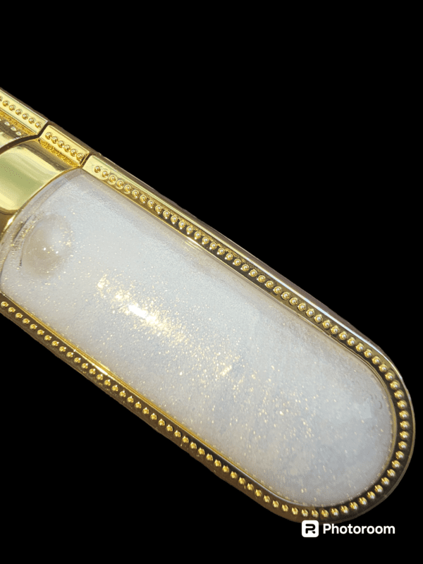 Gold-rimmed bottle of white glitter lip gloss.